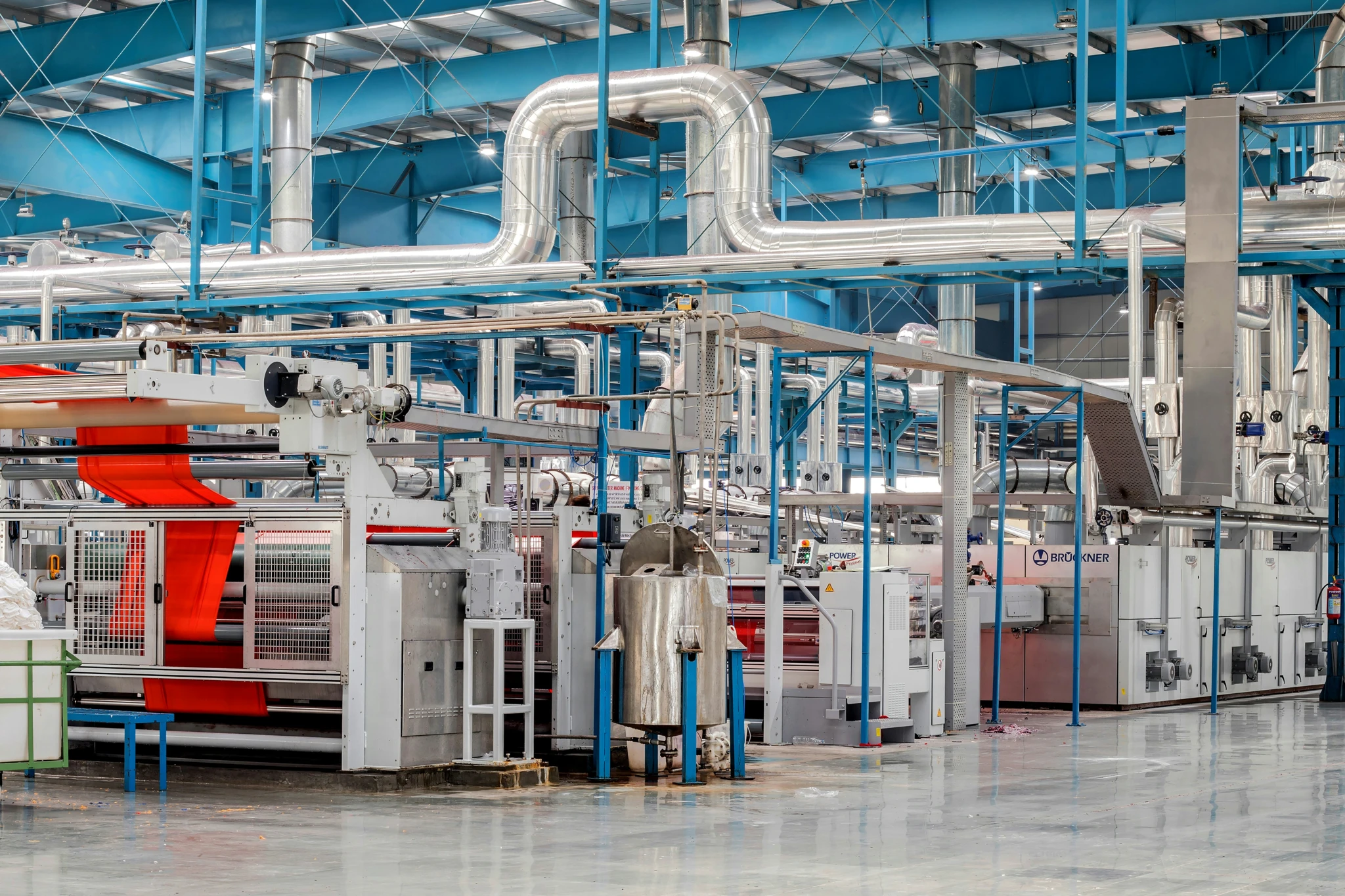 Maszyna w fabryce produkująca materiały kompozytowe przy użyciu zaawansowanej technologii i inżynierii. Stalowe rury na obrazie reprezentują masową produkcję w przemyśle.